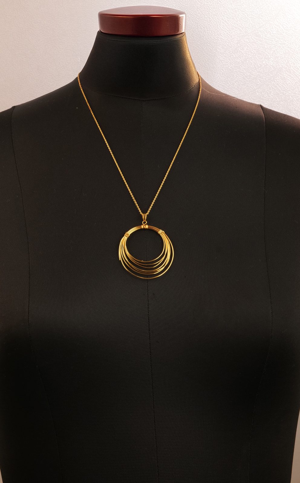 Before: gold hoop pendant on a black mannequin