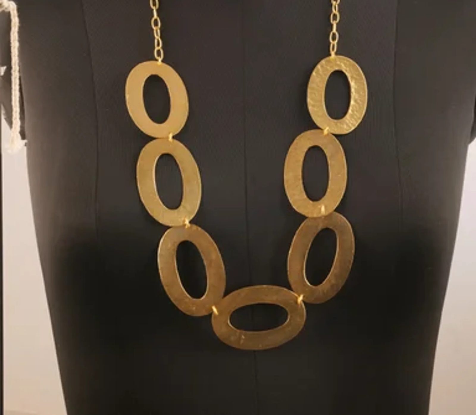Before: gold oval necklace on a black mannequin